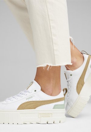Baskets blanches avec un cuir texturé blanc, des accents beige et vert menthe, une semelle plateforme épaisse et un logo Puma bien en évidence sur le côté.
