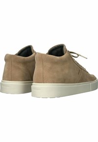 Zapatillas altas de gamuza color marrón claro con una suela de goma blanca, que cuentan con cordones planos y un interior suave. La marca es mínima.