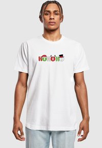 Hvid bomulds t-shirt med "HO HO HO" i rød, grøn og sort, med festlige detaljer såsom en julesok og rensdyrhorn.