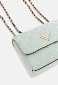 Borsa trapuntata verde chiaro con pattina pieghevole, dettagli in metallo dorato e tracolla a catena con design intrecciato.