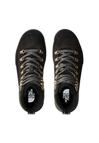 Bottines de randonnée noires avec des accessoires dorés et des lacets noirs et argentés. Design robuste avec une semelle épaisse et un intérieur rembourré.