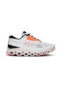 Chaussure de sport blanche avec des accents noirs et des détails orange. Présente une tige en mesh respirant, une semelle rembourrée et un design de semelle intermédiaire unique avec des zones creusées.
