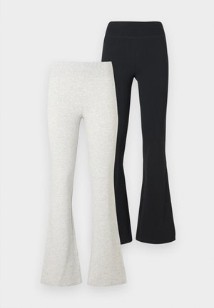 Dwie pary spodni dzwonów, jedna w jasno szarym kolorze, a druga czarna, ustawione obok siebie na jednolitym białym tle.