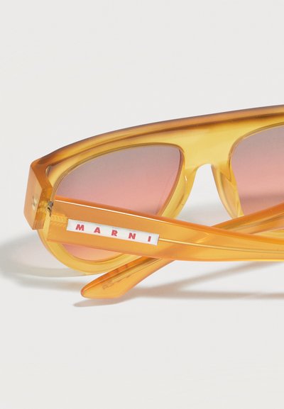 Translucent amber sunglasses with pink-tinted lenses, folded arms, and "MARNI" logo in red on a white background on the temple.