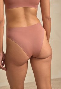 Light pink stretch fabric high-waisted underwear with a smooth texture and minimalist design, featuring a seamless waistband.