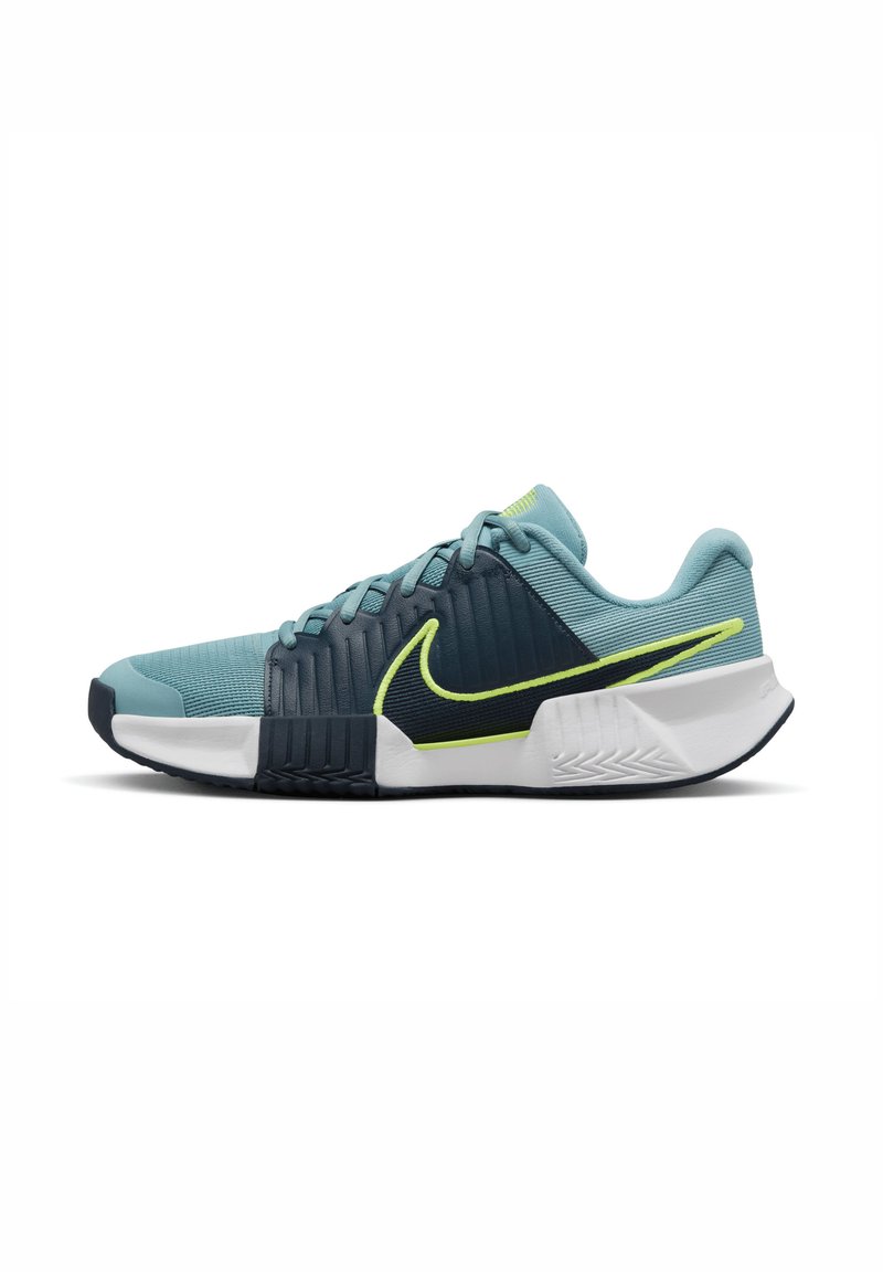 Nike sporta apavi gaiši zilos un tumši zilajos toņos, ar teksturētu virsu, baltu zoli un neona dzelteniem akcentiem. Zemu topa dizains ar aukliņām.
