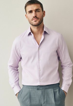 Helllilahe Hemd mit Karomuster, Button-Down-Kragen und langen Ärmeln, kombiniert mit grauen Hosen.
