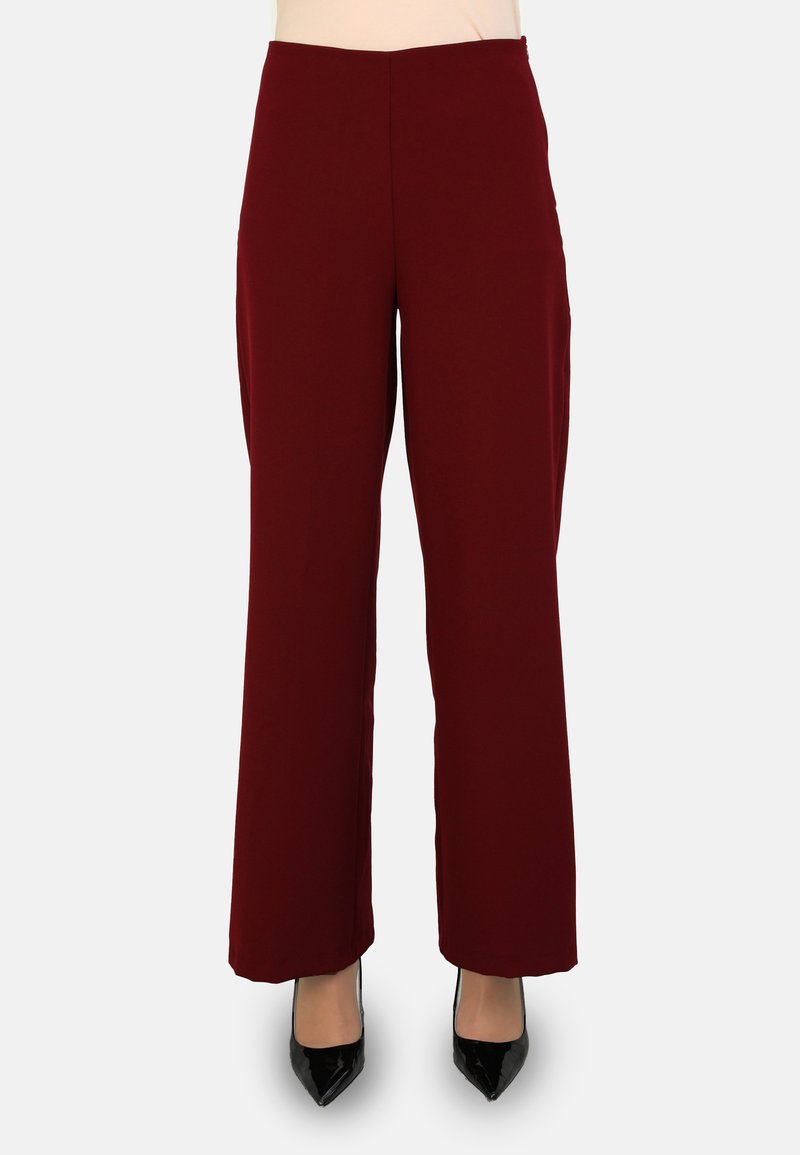 Pantalones anchos burdeos con una textura suave, cintura alta y bolsillos laterales, combinados con tacones negros de punta.