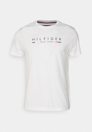 Vit bomullströja med korta ärmar, med ett grafiskt tryck av "HILFIGER NEW YORK" i svart och röd text över bröstet.