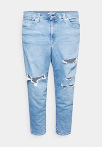 Jean en denim bleu clair avec des déchirures usées sur les deux jambes et un style cinq poches standard sur fond blanc.