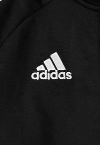 Zwart sportstof met een gestructureerd oppervlak, voorzien van een wit geborduurd Adidas-logo en drie strepen in een driehoekig ontwerp.