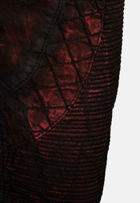 Tessuto nero testurizzato con accenti rosso scuro, caratterizzato da un motivo a griglia e elementi di design curvi, che enfatizzano la profondità e i dettagli del tessuto.