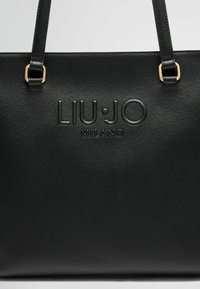 Borsa a tracolla nera realizzata in pelle sintetica testurizzata. Presenta accessori in tonalità oro e logo impresso “LIU•JO MILANO” sulla parte anteriore.