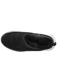 Svart slip-on sko med en kviltad design, fuskpälsfoder och en vit gummisula. Har en dragkedjestängning för enkel påtagning.