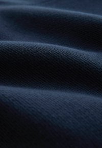 Tissu texturé bleu marine avec un léger nervurage diagonal. Surface lisse avec un tombé doux et une légère brillance. Couleur riche et profonde.