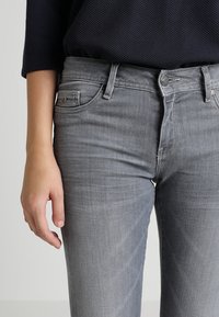 Harmaat farkut slim fit -mallilla, joissa on viisi taskua, nappisuljenta ja hienovarainen haalistuminen sileällä pinnalla.