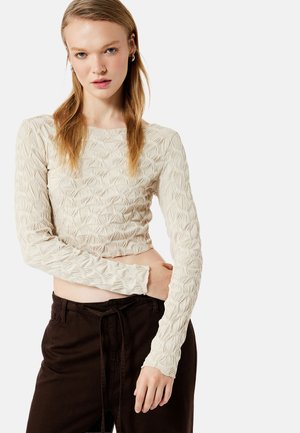 Crème-kleurig langemouwen top met een gemêleerd ruitpatroon, cropped ontwerp en aansluitende mouwen, gecombineerd met bruin met trekkoord.