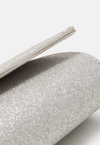 Clutch argento glitter con una zip metallica liscia, bordi arrotondati e superficie texturizzata, che mostra un effetto scintillante in tutto il suo insieme.