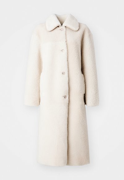 Ilgas kreminės spalvos paltas, pagamintas iš minkštos, tekstūruotos medžiagos. Turi apykaklę, mygtukų užsegimą ir šonines kišenes.