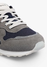 Zapatillas de ante gris con acentos de malla azul marino, cordones blancos y una suela de goma ligera. Presenta costuras a lo largo de la parte superior y una superficie texturizada.