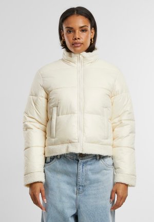 Kraftigt puffer-jakke i creme med quiltet design, sidelommer og blød fleece-kant ved kraven og kanten. Glat ydre tekstur.