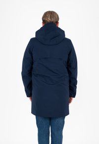 Parka impermeabile blu navy con cappuccio, caratterizzata da una linea dritta, maniche lunghe e un design con yoke posteriore. Stile minimalista; nessun hardware visibile.