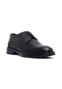 Zwarte leren veterschoenen met een gestructureerde afwerking, ronde neus en een dikke rubberen zool met grippatronen.