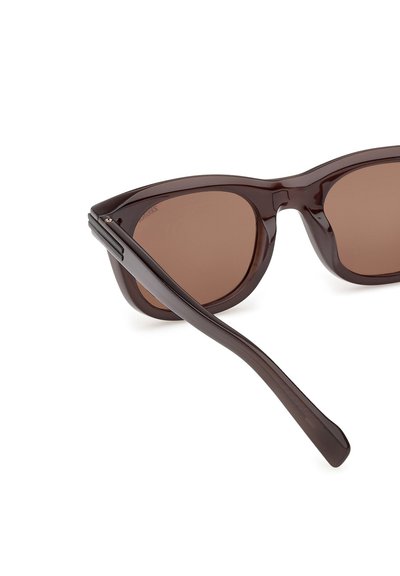 Brązowe plastikowe okulary przeciwsłoneczne o kocim kształcie, ciemnobrązowe soczewki i smukła, szeroka rama. Minimalnie widoczne elementy metalowe.