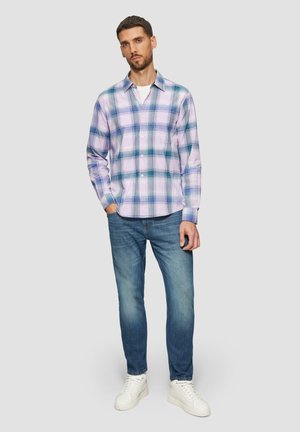 Lichtpaarse geruite blouse met groene en blauwe accenten, met een knoopsluiting op de kraag, gedragen met blauwe jeans en witte sneakers.