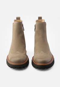 Bottines en suède gris avec un bout rond, des accents en cuir marron, des panneaux latéraux en élasthanne et une semelle en caoutchouc noir texturé.