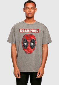Hall vasakpoolne särk, millel on punane ja must maskuliinne kamuflaažiga Deadpool'i graafika valgete silmadega ning "DEADPOOL" tekst üleval.