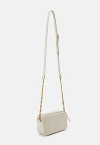 Cream-colored leather crossbody bag with a chain strap, rectangular shape, zip closure, and embossed logo on the front.