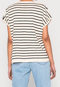 Gestreiftes T-Shirt mit kurzen Ärmeln in Creme mit schwarzen horizontalen Streifen; lockere Passform, weiche Textur, Rundhalsausschnitt und umgeschlagene Ärmel.