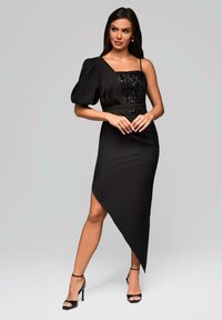 Schwarzes Kleid mit einem Pailletten-Oberteil, einem Puffärmel und einem asymmetrischen Saum. Glatte Textur mit einer figurbetonten Silhouette.