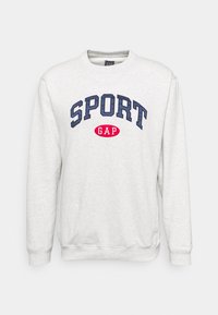 Sweat-shirt gris en polaire avec col rond. Présente "SPORT" en bleu foncé et "GAP" en rouge sur la poitrine. Poignets et ourlet côtelés.