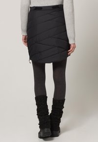 Černá prošívaná sukně s diagonálním šit�ím, spojená se šedými legíny a černými pletenými návleky na nohy. Obsahuje elastický pas a detail se zipem.