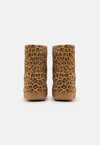 Bottines en cuir léopard de couleur beige avec des accents noirs. Texture de tissu douce et semelle en caoutchouc robuste. Conçues avec un bout rond et un talon bas.