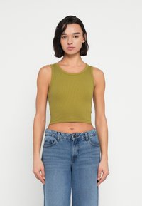 Ελιά πράσινο ριμπ crop top με στρογγυλή λαιμόκοψη, σε συνδυασμό με ανοιχτό μπλε τζιν παντελόνι με φαρδιά μπάρα, με κλασικό κούμπωμα με κουμπιά και φερμουάρ.