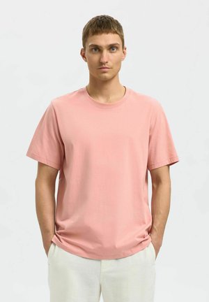 Lyserød kortærmet T-shirt lavet af blødt bomuld. Rund halsudskæring og afslappet pasform, med glat, ensartet overflade og ingen synlige mønstre.