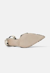 Scarpa con tacco alto a punta, con un motivo in pelle di serpente beige e nero. Suola beige liscia e sottili cinturini neri che attraversano il piede.
