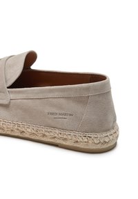 Lichtgrijze suède instap schoen met een gevlochten jute zool, voorzien van een gestikte rand en een gegraveerd logo aan de zijkant. Over het geheel een gladde textuur.