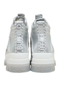 Een paar zilveren chunky sneakers met dikke witte zolen, merk "Buffalo" op de hak en stoffen pulltabs aan de achterkant.