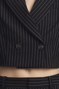 Blazer corto nero con righe bianche, design doppiopetto e due bottoni neri. Tessuto liscio con vestibilità su misura.