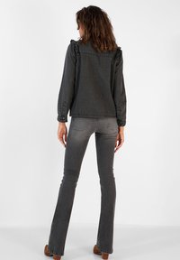 Flared gray denim jeans with a smooth texture and subtle stitching details, paired with a matching gray, frill-accented denim jacket.