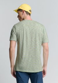 Gestreepte groen-witte t-shirt met korte mouwen en een ronde hals, gemaakt van zachte stof. Gekocht met een gele pet, wat een casual uitstraling geeft.
