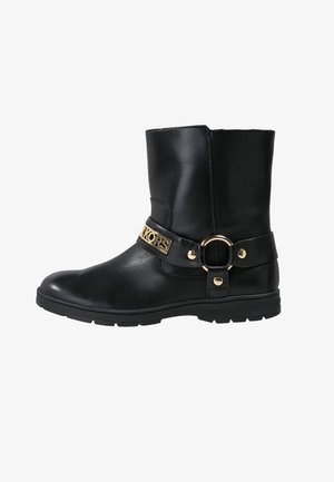 Botte de cheville en cuir noir avec une sangle logo en ton doré, un détail de matériel rond, une finition texturée, et une semelle en caoutchouc robuste.