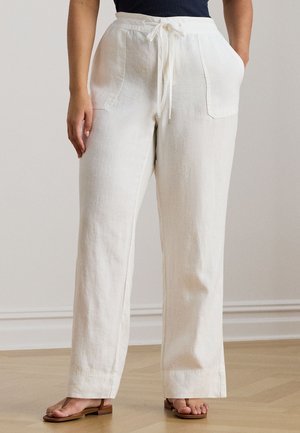 Weiße Leinenhose mit weitem Bein, Kordelzug in der Taille und zwei Seitentaschen, aus einem leichten, strukturierten Stoff. Kombiniert mit braunen Sandalen.