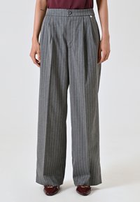 Graue Nadelstreifenhose mit hoher Taille, Faltenwurf, Knopfverschluss und lässiger Passform. Das Material wirkt strukturiert.