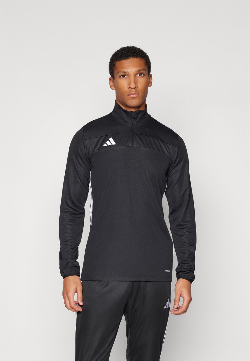 Czarny sportowy top z zamkiem błyskawicznym na ćwiartkę i długimi rękawami, z teksturowaną górną częścią oraz białymi paskami po bokach. Logo Adidas na klatce piersiowej.