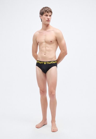 Culottes noires avec une ceinture jaune à motif, design ajusté, fabriquées à partir d'un matériau lisse, avec une couleur unie sur l'ensemble.